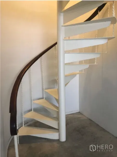 Shophouse for rent in Watthana, Bangkok - White spiral staircase with dark handrail connecting floors.