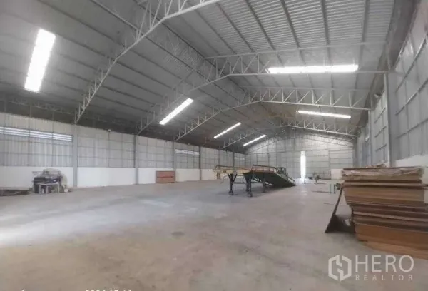 Warehouse for sale in Sai Noi, Nonthaburi - Spacious warehouse interior with high steel trusses, skylights and clear open floor.