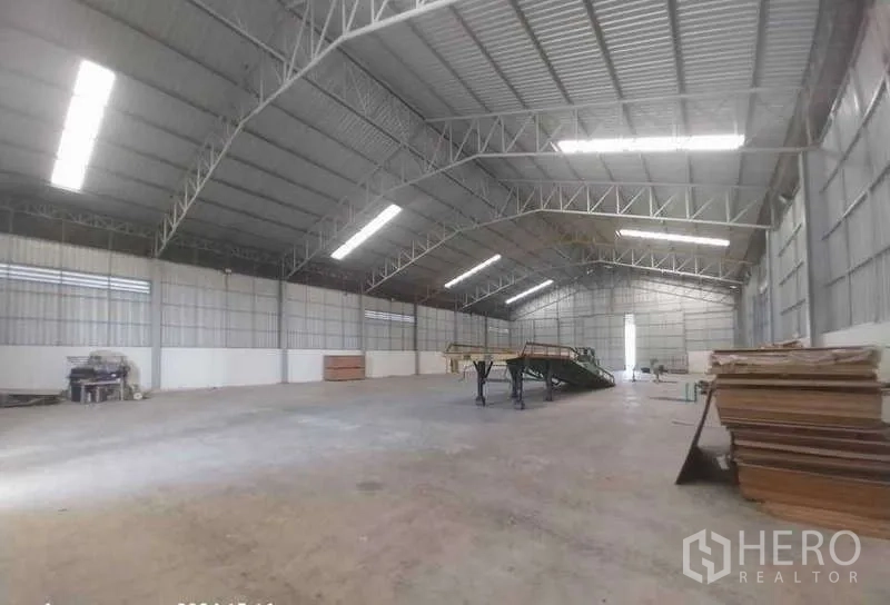 Warehouse for sale in Sai Noi, Nonthaburi - Spacious warehouse interior with high steel trusses, skylights and clear open floor.