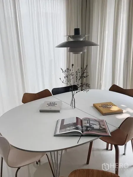 Detached House for sale in Bang Kapi, Bangkok - Sunlit dining area with oval white table, pendant lamp, and wooden chairs.