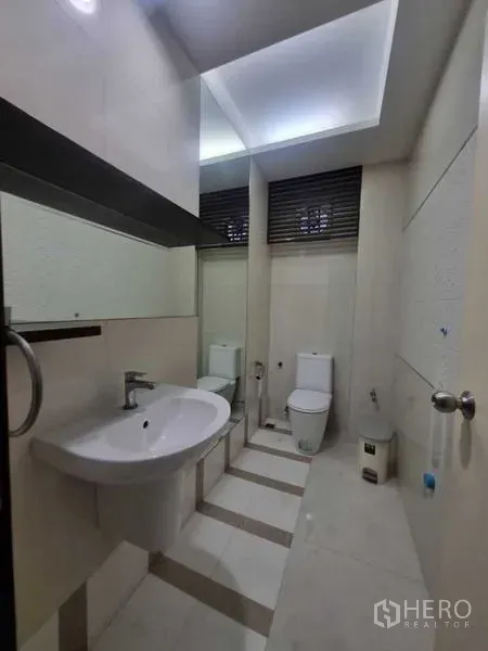 Shophouse for rent in Watthana, Bangkok - Clean restroom featuring a wall mirror, ceramic sink, and toilet.