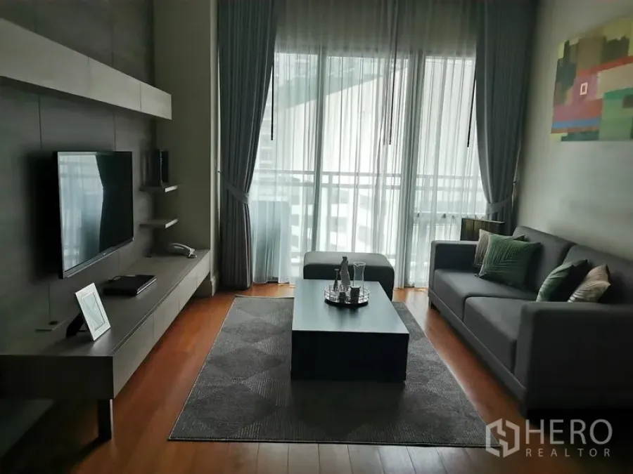 Condominium for rent in Khlong Toei, Bangkok - Modern living room in Khlong Toei, Bangkok condo with grey sofa, TV wall, coffee table and balcony glazing.