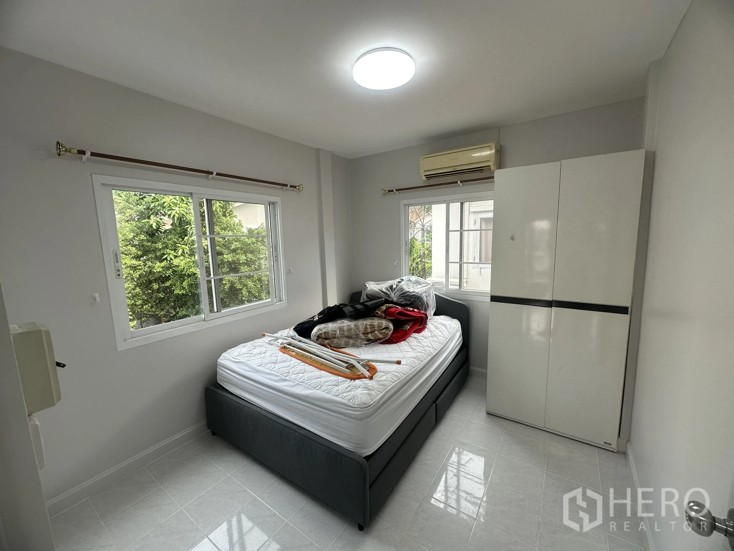 Townhouse for sale in Lam Luk Ka, Pathum Thani - Second bedroom with large windows, bed and wardrobe.