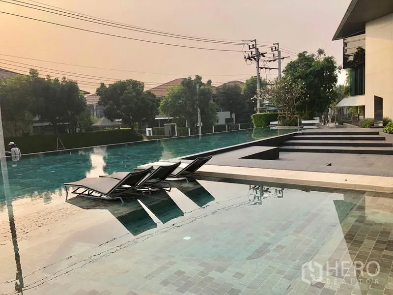 Detached House for rent or sale in Bang Kapi, Bangkok - Long resort-style swimming pool with sun loungers within the residential community.