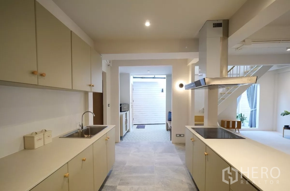 Townhouse for rent or sale in Watthana, Bangkok - Galley kitchen with twin counters, upper cabinets and stainless sink.