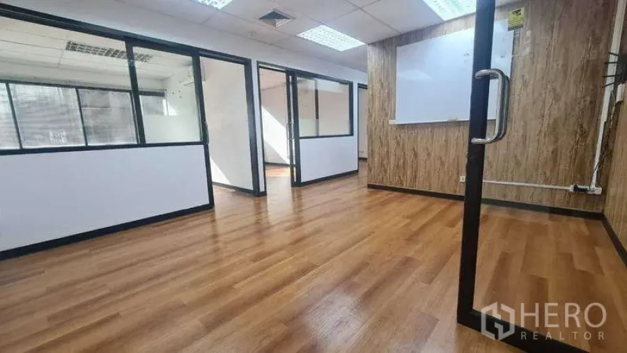 Office Space for rent in Khlong Toei, Bangkok - Main office zone showing multiple glass partitions, white walls, and warm flooring.