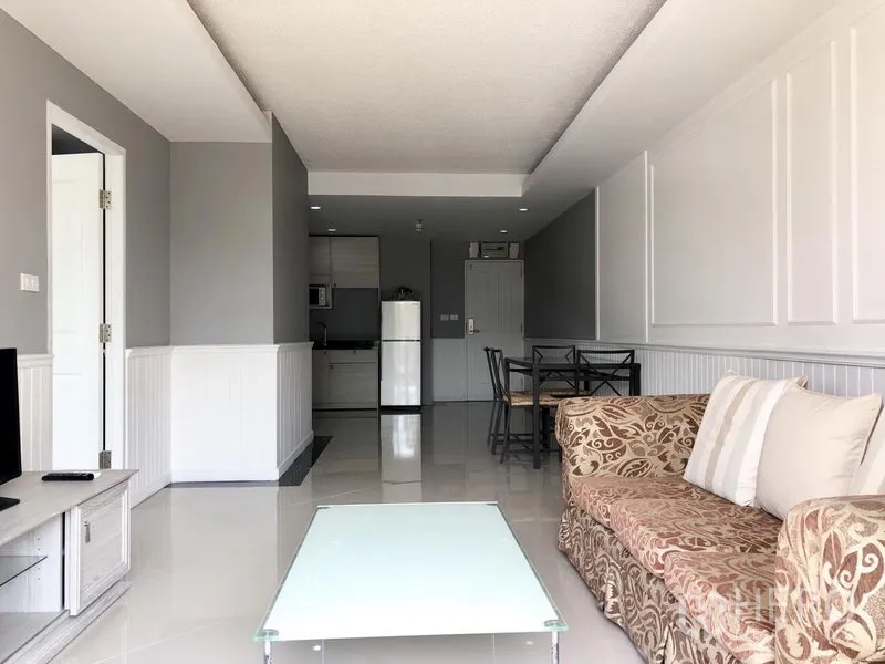 Condominium for rent in Khlong Toei, Bangkok - Open-plan living area with sofa, glass coffee table and kitchenette in a bright Waterford Sukhumvit 50 condo near BTS On Nut.