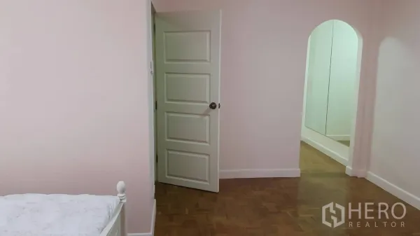 Townhouse for rent in Khlong Toei, Bangkok - Bedroom corridor with pink walls, a white door, and an arched mirror niche.