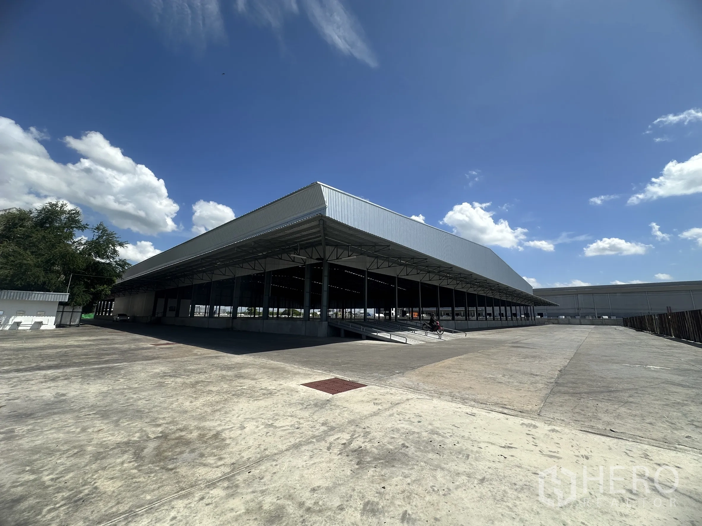 Warehouse for rent in Wang Noi, Phra Nakhon Si Ayutthaya - Angled exterior view showing loading ramps and an extensive driveway beside the warehouse.