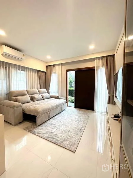 独立式住宅 出租在Bang Phli, Samut Prakan - 采光充足的起居室，大型沙发、纱帘及通向花园的推拉门。
