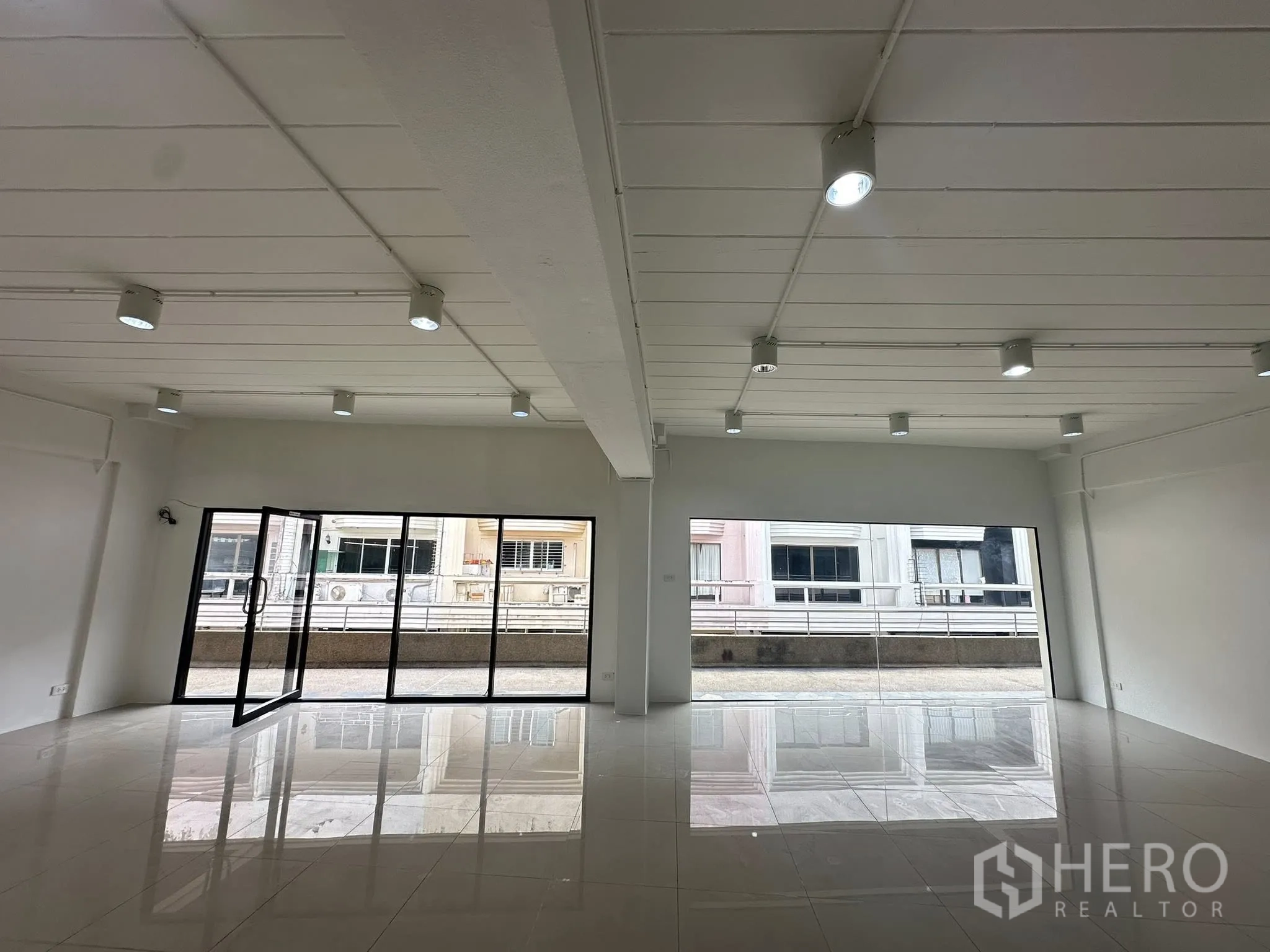 Office Space for rent in Watthana, Bangkok - Double-aspect office with two expansive glass walls and reflective tile flooring.