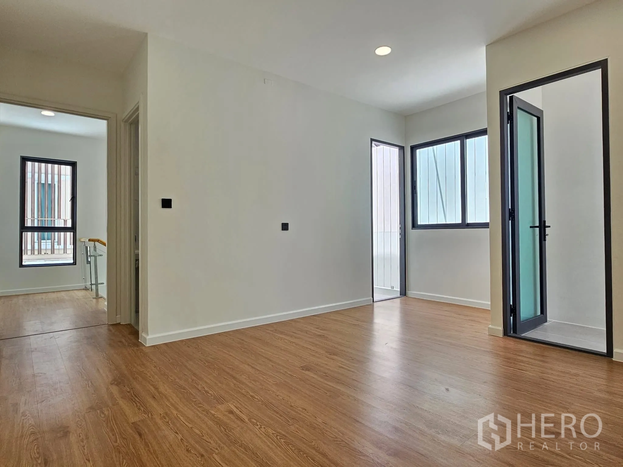Detached House for sale in Lat Phrao, Bangkok - Upstairs landing area with wood floors, multiple windows, and doors leading to bedrooms and a terrace.