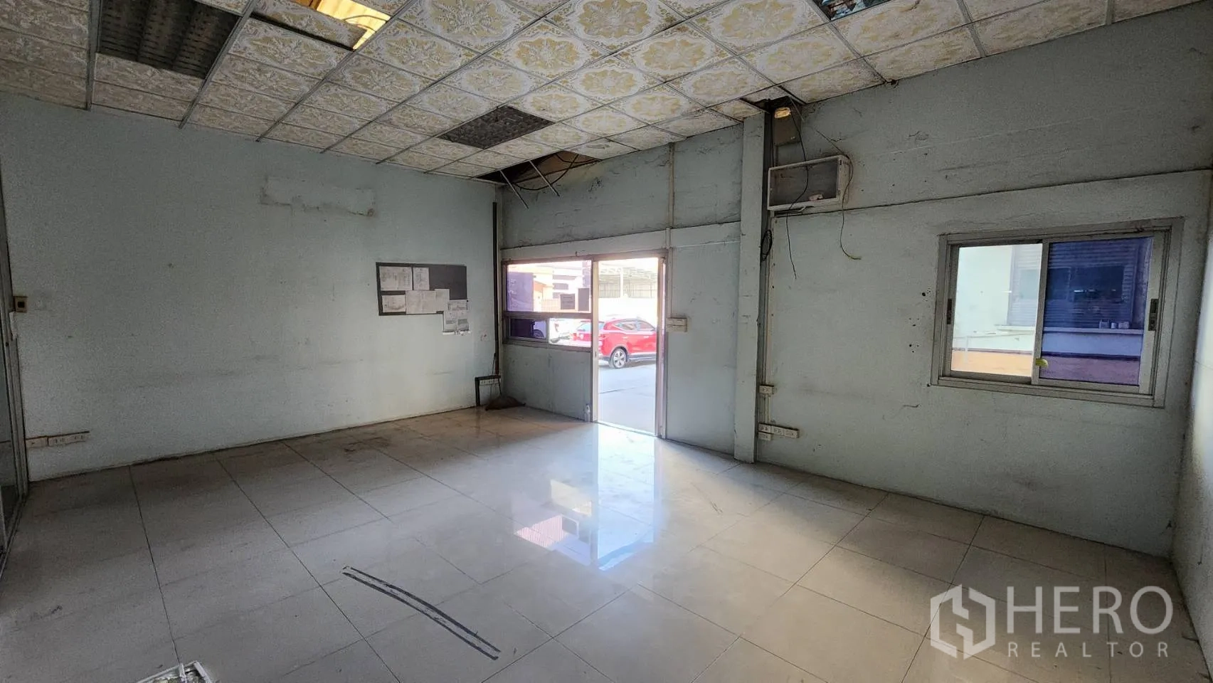 Warehouse for rent in Nonthaburi - Basic office room with tiled floor and suspended ceiling panels.
