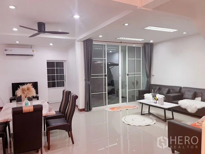Townhouse for rent in Huai Khwang, Bangkok - Living room facing full-height sliding doors opening to the carport.