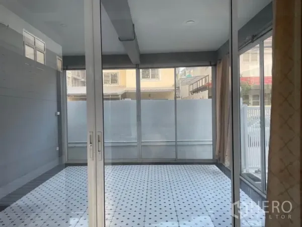 Detached House for rent in Huai Khwang, Bangkok - Bright enclosed room with floor-to-ceiling windows and patterned white tile flooring.