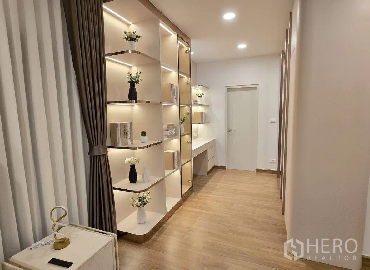 Detached House for rent or sale in Bang Phli, Samut Prakan - Hallway with illuminated built‑in shelving, work desk and wood floors.