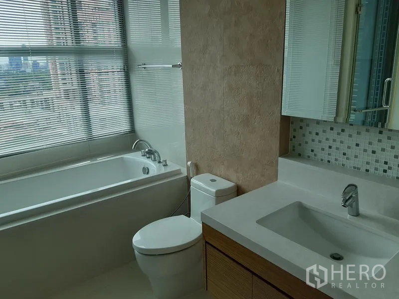 Condominium for rent or sale in Khlong Toei, Bangkok - Second bathroom with bathtub by the window, mosaic backsplash and vanity with sink.