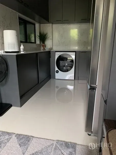 Townhouse for rent in Suan Luang, Bangkok - Modern kitchen and laundry zone with glossy cabinetry, a front-load washer and stainless refrigerator.