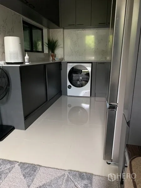 Townhouse for rent in Suan Luang, Bangkok - Modern kitchen and laundry zone with glossy cabinetry, a front-load washer and stainless refrigerator.
