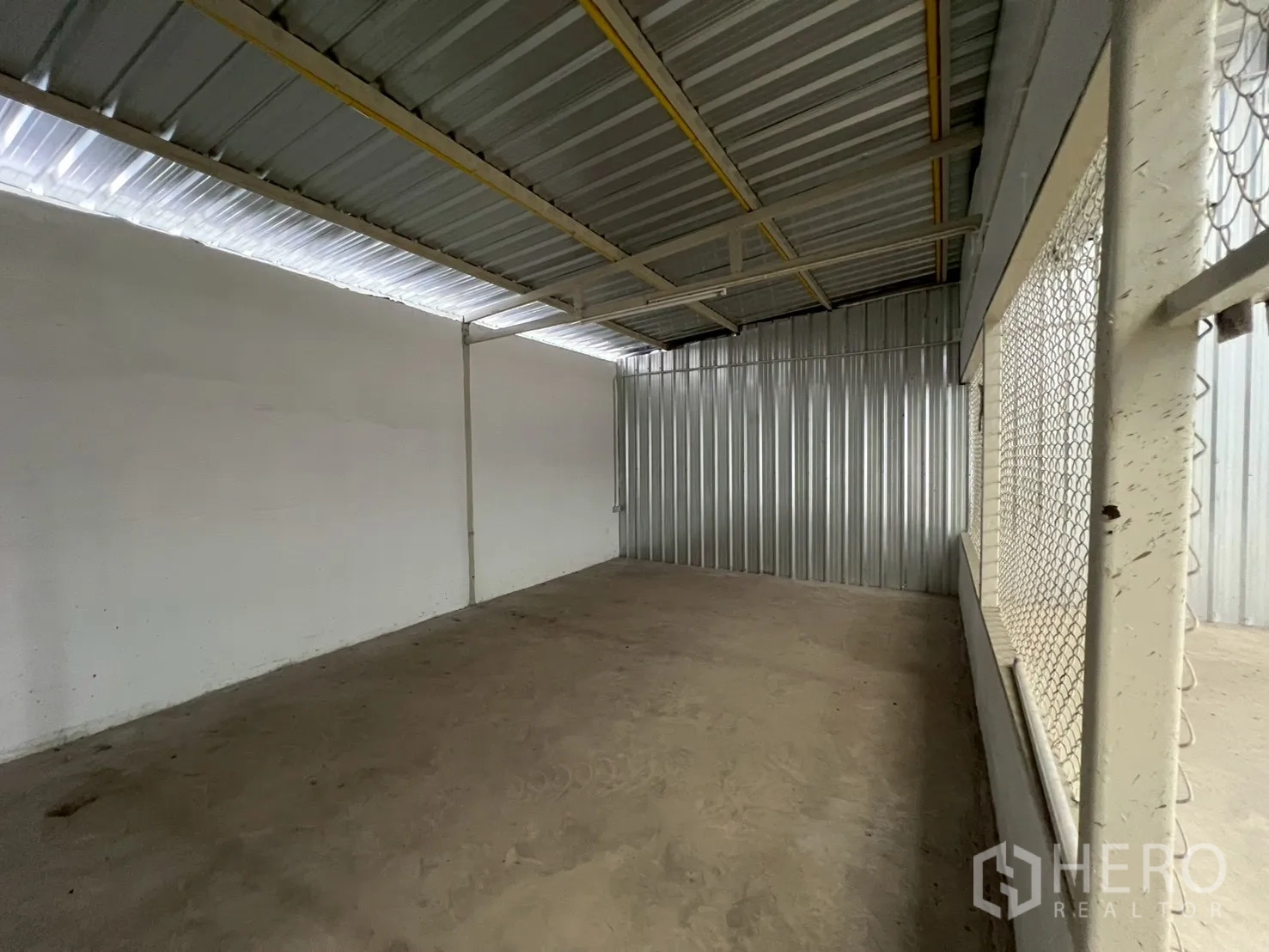 Warehouse for rent in Min Buri, Bangkok - Large enclosed room with chain-link windows and metal roof, ideal for office or inventory.