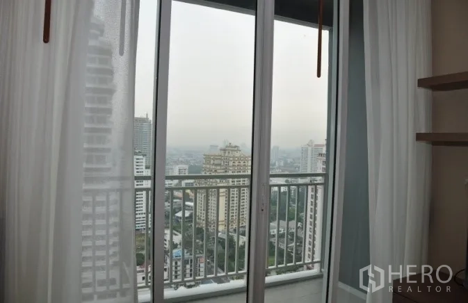 Condominium for rent or sale in Watthana, Bangkok - Sliding doors opening to a balcony with city skyline panorama.