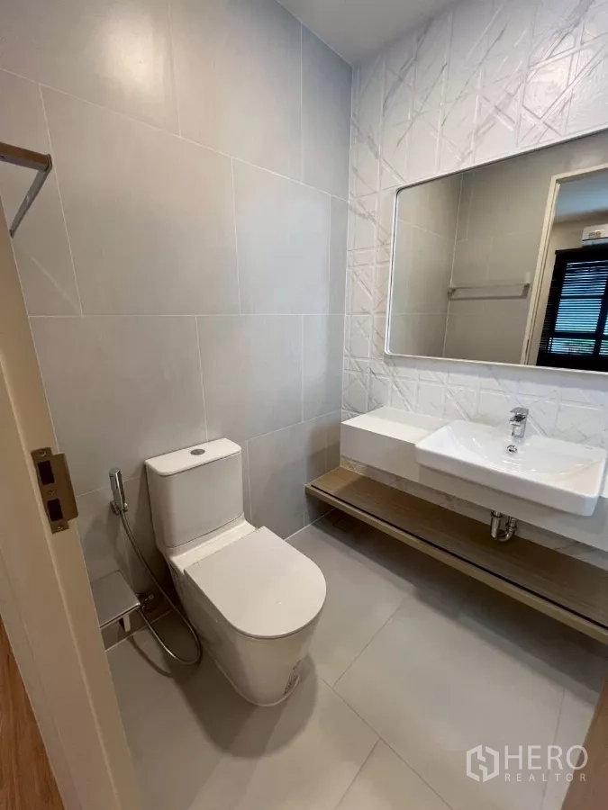 Detached House for rent in Samut Prakan - Powder room with toilet, basin, and large mirror.