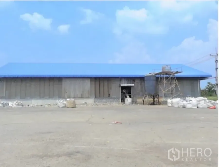 Factory for sale in Phanat Nikhom, Chon Buri - Front view of the factory shed with blue roof and spacious truck turning area.