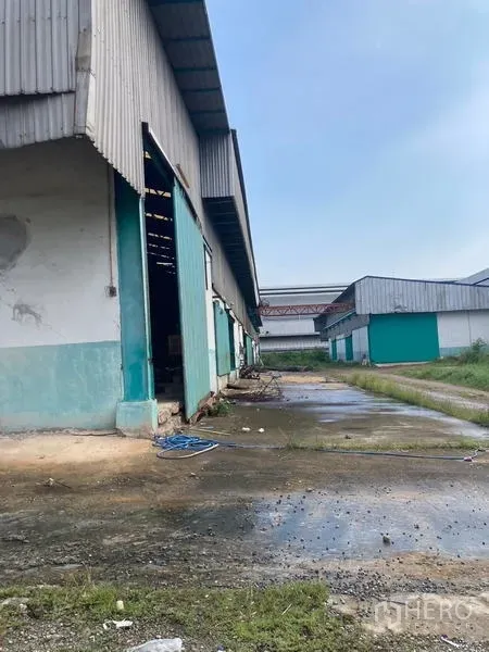 Warehouse for rent in Mueang Samut Sakhon, Samut Sakhon - Side service lane along a corrugated metal warehouse with drainage and access path.