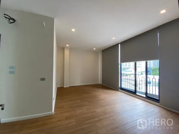 Home Office for rent or sale in Watthana, Bangkok - Spacious workspace with floor‑to‑ceiling windows opening to a small balcony and city views.