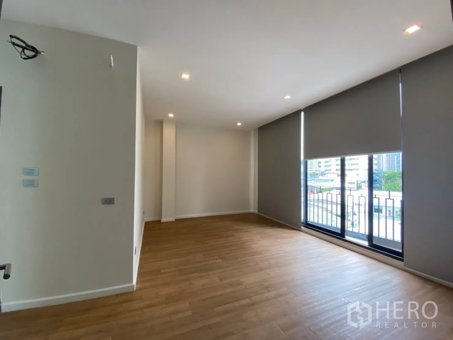 Home Office for rent or sale in Watthana, Bangkok - Spacious workspace with floor‑to‑ceiling windows opening to a small balcony and city views.