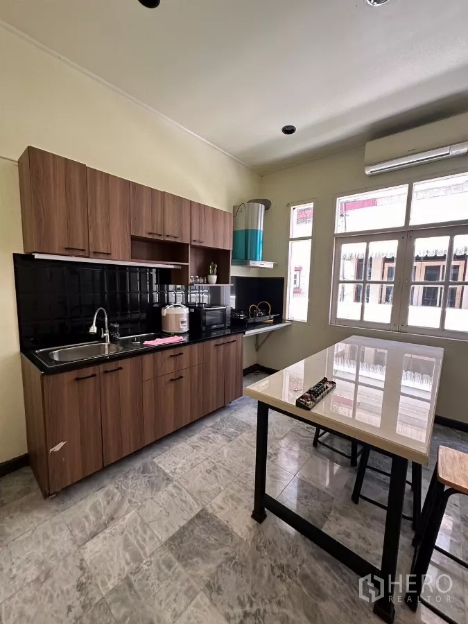 Home Office for rent in Suan Luang, Bangkok - Main kitchen with wood cabinets, black tile backsplash, and an island.