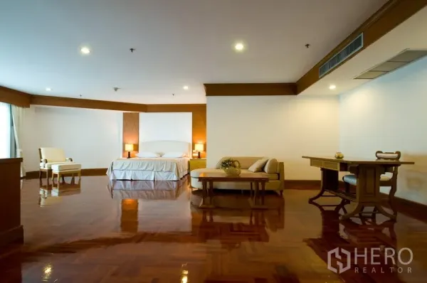 Apartment for rent in Khlong Toei, Bangkok - Expansive master bedroom with polished hardwood floors, seating area and soft lighting.