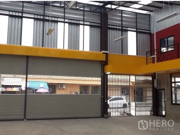 Warehouse for rent in Bang Kapi, Bangkok - High-clearance loading area with roller doors, folding security gate and tall windows.
