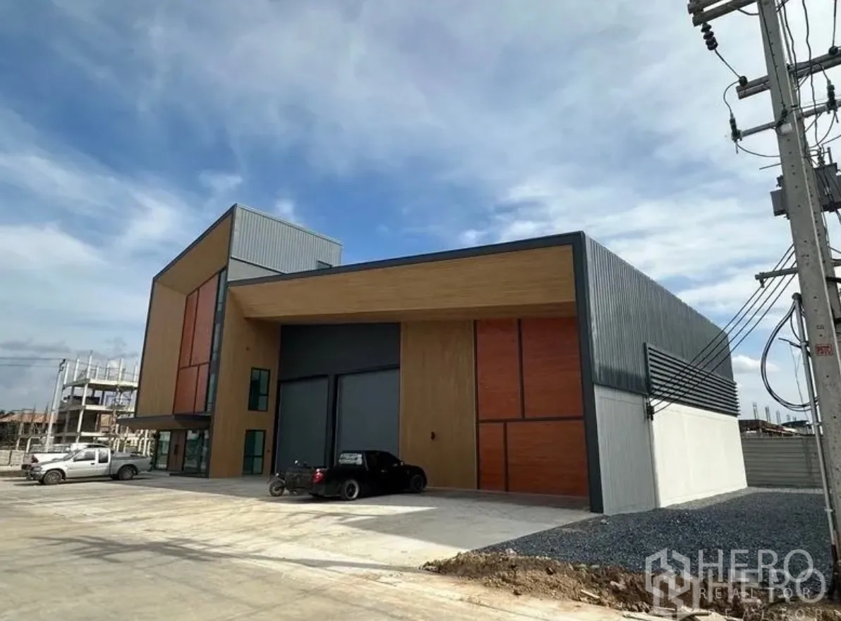 Warehouse for sale in Lam Luk Ka, Pathum Thani - Street-facing facade with oversized roller shutters and covered loading canopy.