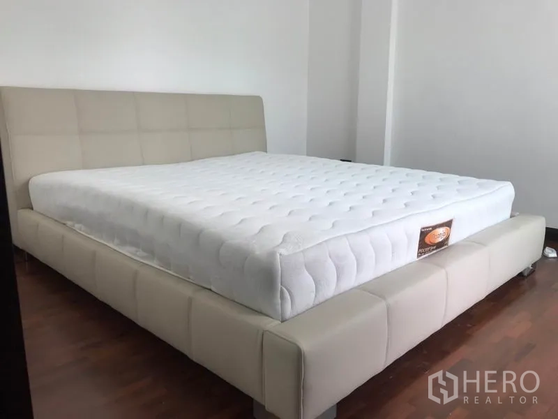 Townhouse for rent or sale in Khlong Toei, Bangkok - Cozy bedroom with upholstered bed on polished wooden flooring.