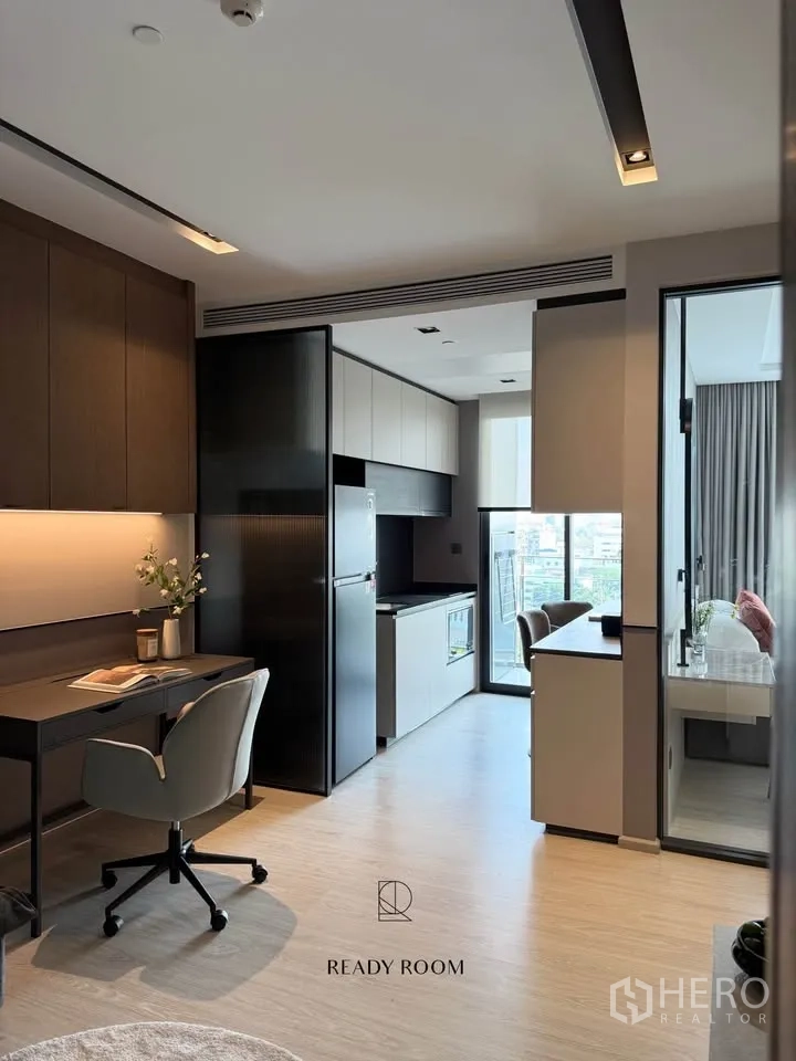 Condominium for rent in Khlong Toei, Bangkok - Open-plan kitchen and workspace with built-in cabinets, refrigerator, and balcony view.