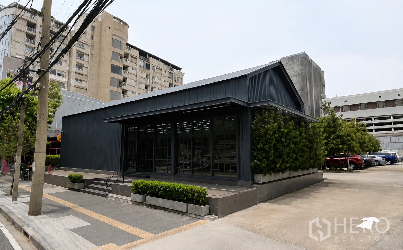 零售空间 for rent in Khlong Toei, Bangkok - 独立现代零售建筑，深色外立面，台阶入口、绿化与旁侧停车区。