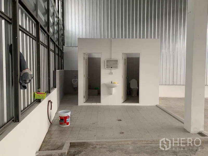 Warehouse for rent in Mueang Pathum Thani, Pathum Thani - On-site restroom block with two toilet stalls, sink and tiled floor inside the warehouse.