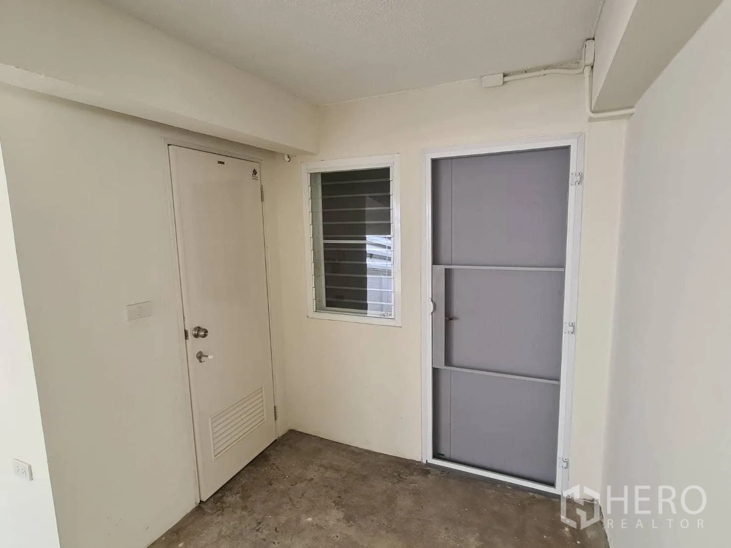 Detached House for rent in Khlong Toei, Bangkok - Service entrance with two doors and a louvered window beside the carport.