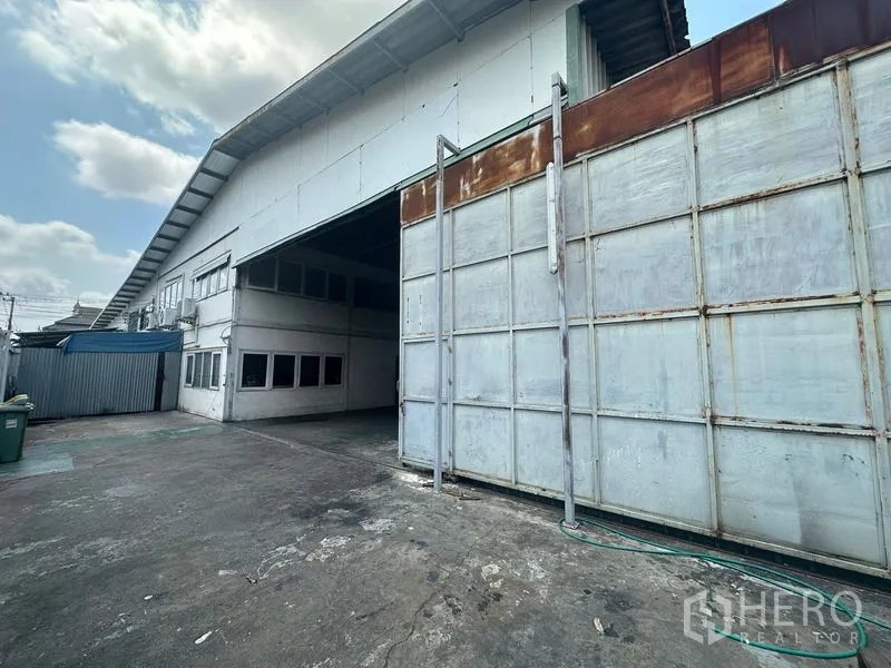 Warehouse for rent in Suan Luang, Bangkok - Close view of the warehouse entrance and sliding gate with concrete forecourt.
