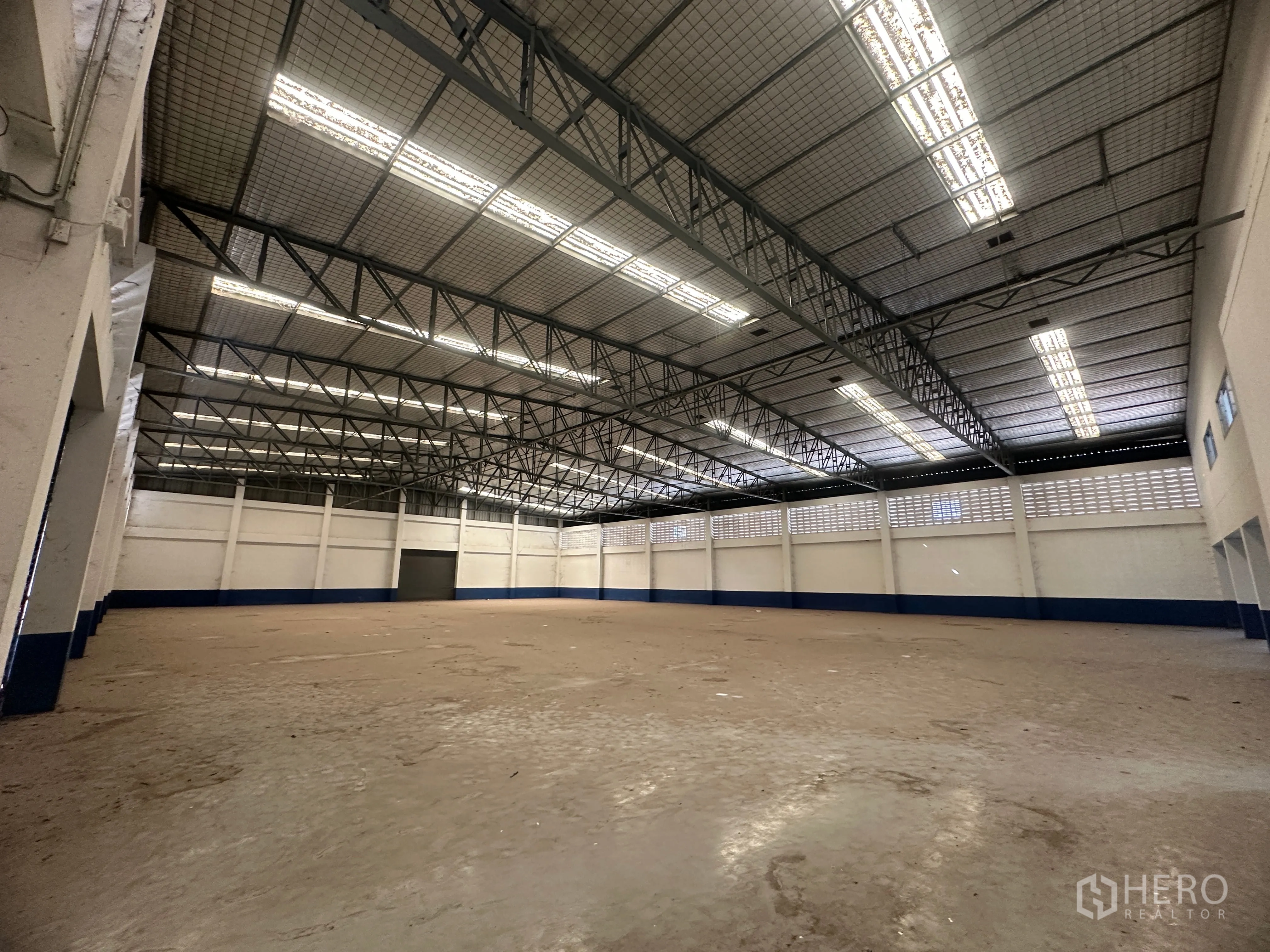 Factory for rent in Bang Pa-in, Phra Nakhon Si Ayutthaya - Spacious warehouse hall with steel truss roof, fluorescent lights, and ventilated walls.