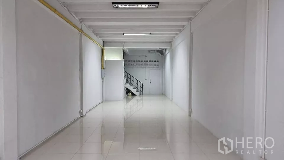 Townhouse for rent in Huai Khwang, Bangkok - Deep open-plan living area with tiled floor and a staircase at the back.