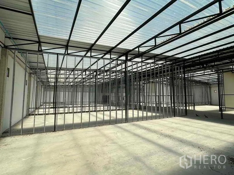 Warehouse for rent in Sai Noi, Nonthaburi - Spacious production zone with steel columns and clear span beneath skylight roof panels.