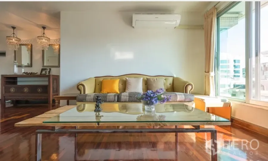 Condominium for rent in Pathum Wan, Bangkok - Sunlit living room with vintage sofa, glass coffee table and warm wood floors.