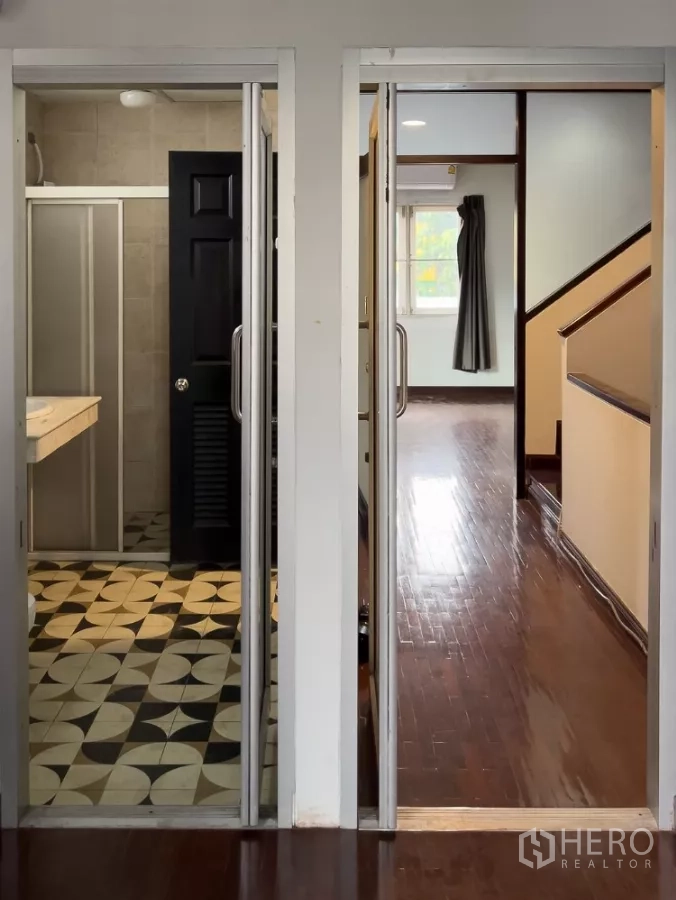Home Office for rent in Lat Phrao, Bangkok - Corridor showing a patterned-tile bathroom and wooden staircase to upper floors.