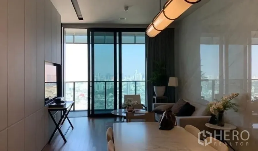 Condominium for sale in Khlong San, Bangkok - Open-plan living and dining with floor-to-ceiling windows, balcony and skyline view in a Khlong San condo.