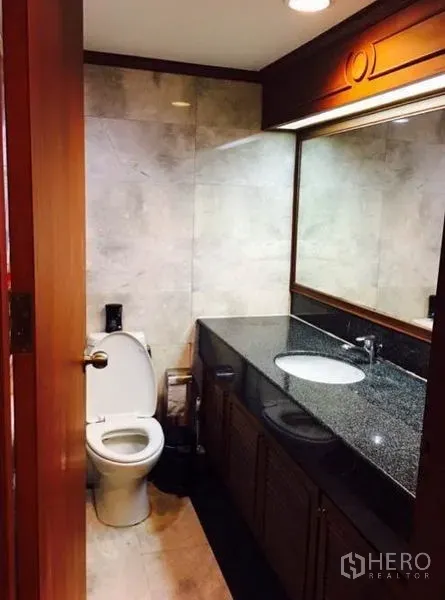 Condominium for rent or sale in Watthana, Bangkok - Bathroom with granite countertop vanity, large mirror and toilet.