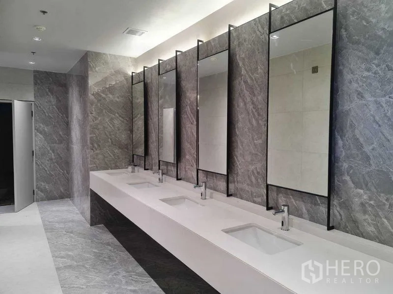 Office Space for rent in Phra Khanong, Bangkok - Modern communal restroom with long vanity, multiple mirrors and taps, grey marble walls.