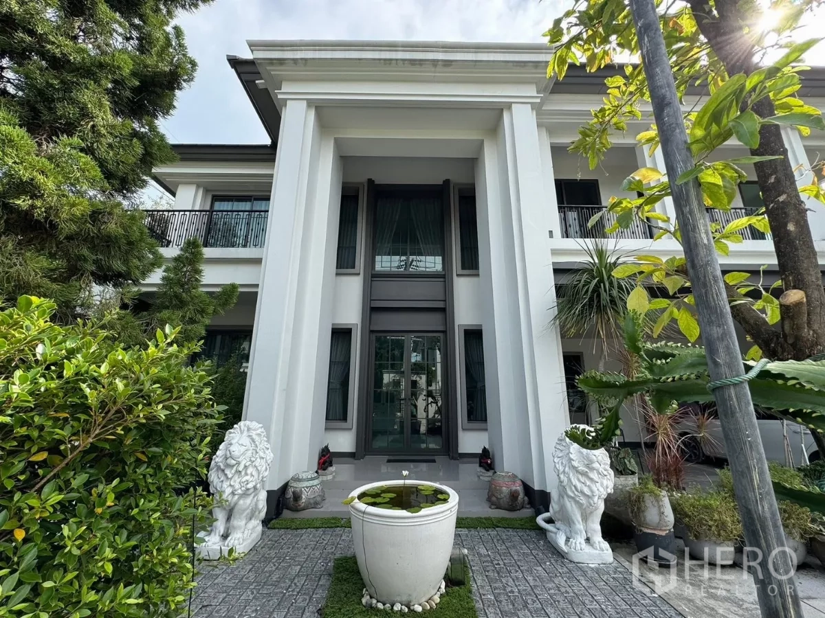 Detached House for sale in Mueang Pathum Thani, Pathum Thani - Grand entry with tall pillars, glass doors and lion statues flanking a garden urn.