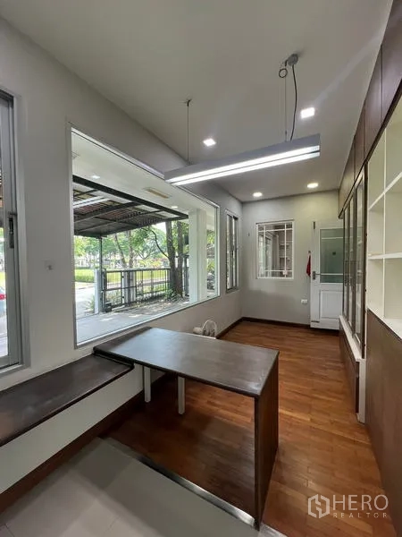 Detached House for rent in Bang Kapi, Bangkok - Glass-wrapped home office or sunroom with built-in shelves and garden view.